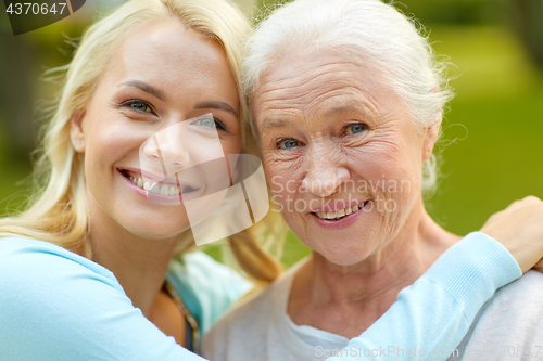 Image of daughter with senior mother hugging on park bench