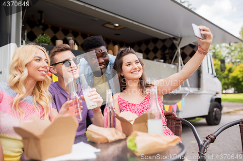 Image of happy young friends taking selfie at food truck