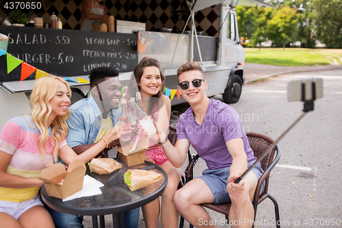 Image of happy young friends taking selfie at food truck