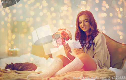 Image of happy woman with flowers and greeting card at home