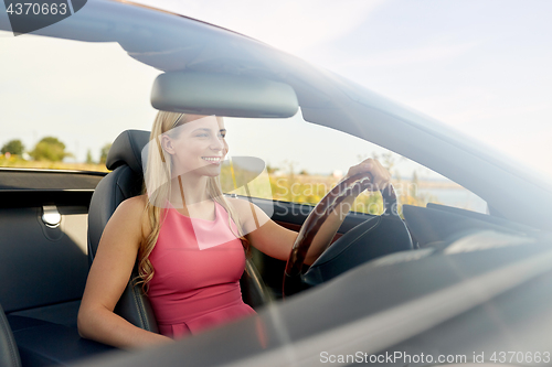 Image of happy young woman driving convertible car