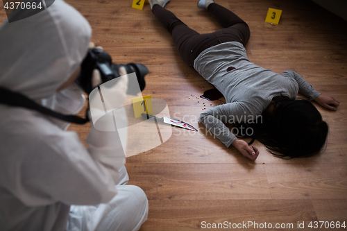 Image of criminalist photographing dead body at crime scene