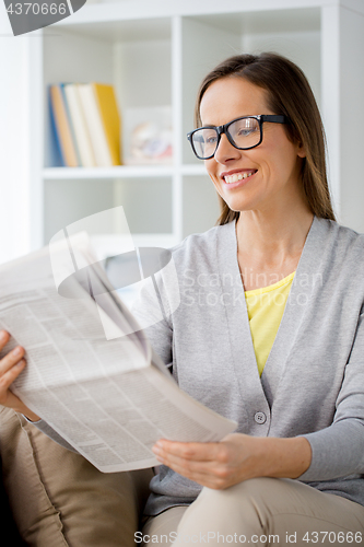 Image of woman in glasses reading newspaper at home