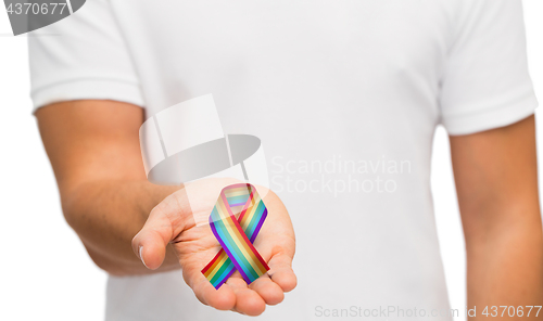 Image of male hand holding gay pride awareness ribbon