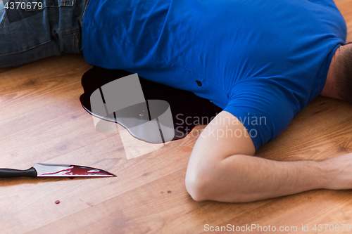 Image of dead man body lying on floor at crime scene