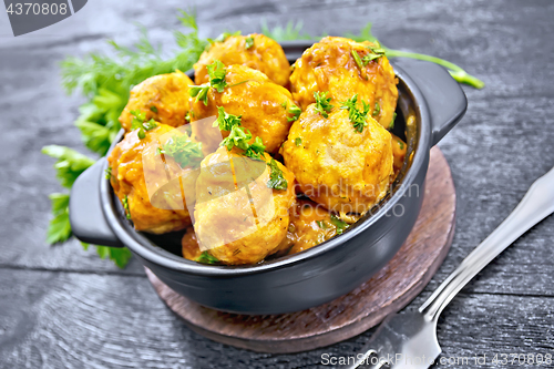 Image of Meatballs in brazier with greens on black board