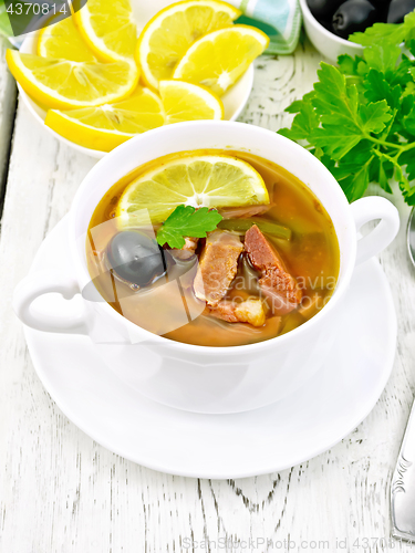 Image of Solyanka with lemon in white bowl on light board