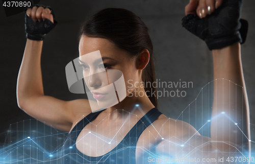 Image of young woman flexing muscles in gym