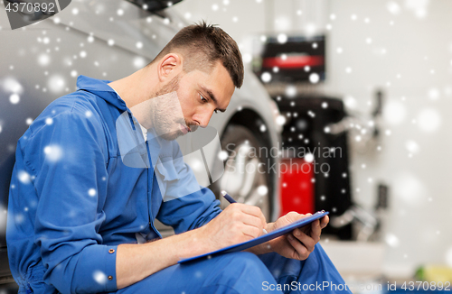 Image of auto mechanic man with clipboard at car workshop