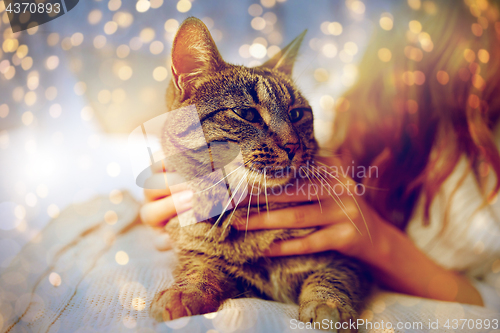 Image of young woman with cat lying in bed at home