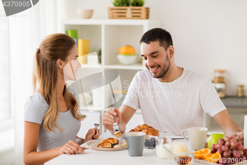 Image of happy couple having breakfast at home