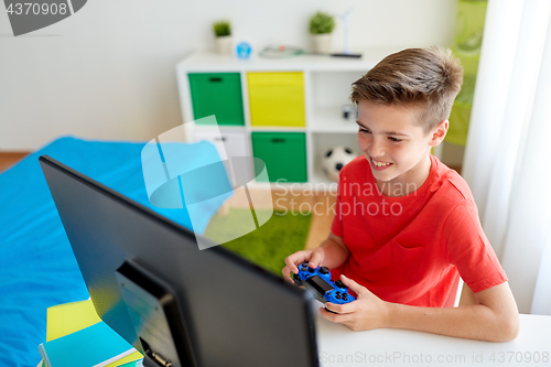 Image of boy with gamepad playing video game on computer