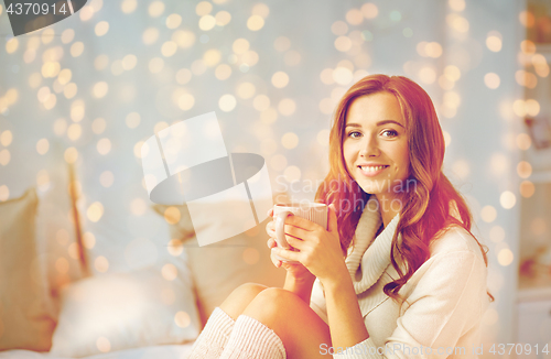 Image of happy woman with cup of coffee in bed at home