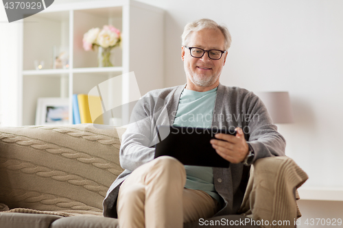 Image of senior man with tablet pc sitting on sofa at home