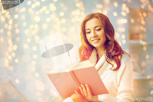 Image of happy young woman reading book at home