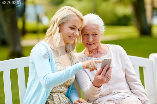 Image of daughter and senior mother with smartphone at park