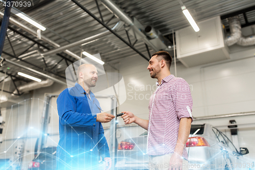 Image of auto mechanic giving key to man at car shop