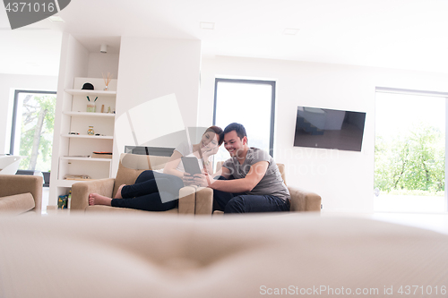 Image of couple relaxing at  home with tablet computers