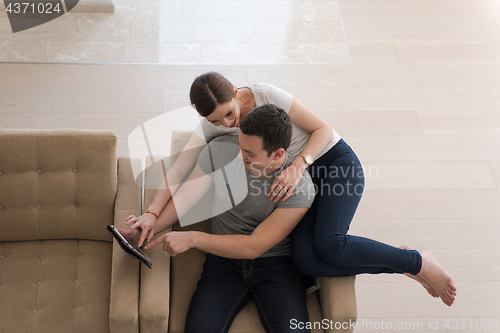 Image of couple relaxing at  home with tablet computers