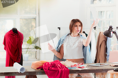 Image of Fashion designers working in studio sitting on the desk