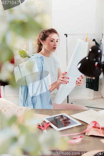 Image of Fashion designers working in studio sitting on the desk