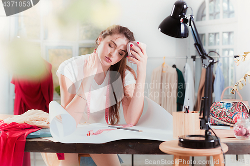 Image of Fashion designers working in studio sitting on the desk