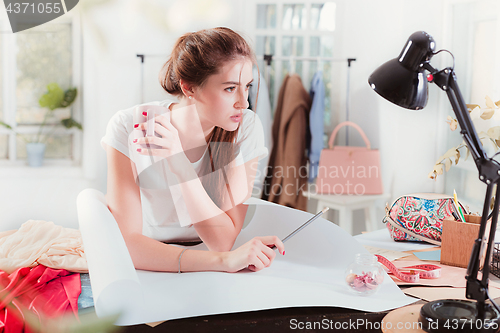 Image of Fashion designers working in studio sitting on the desk