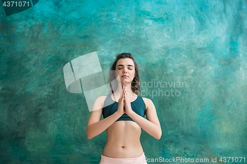 Image of Studio shot of a young woman doing yoga exercises on green background