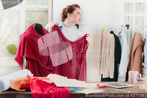 Image of Fashion designers working in studio sitting on the desk