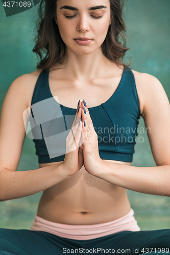 Image of Studio shot of a young woman doing yoga exercises on green background