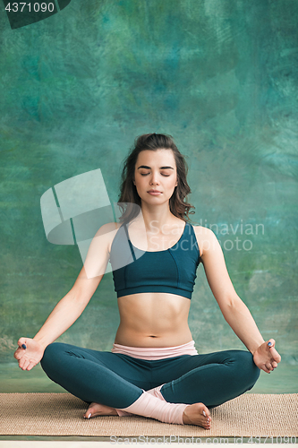 Image of Studio shot of a young woman doing yoga exercises on green background