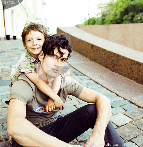 Image of little son with father in city hagging and smiling, casual look