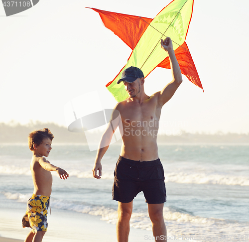 Image of father and son, sunset at the seacoast with kite, happy family 