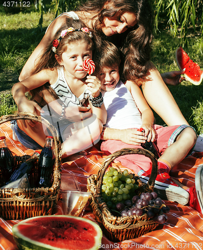 Image of cute happy family on picnic laying on green grass mother and kids, warm summer vacations