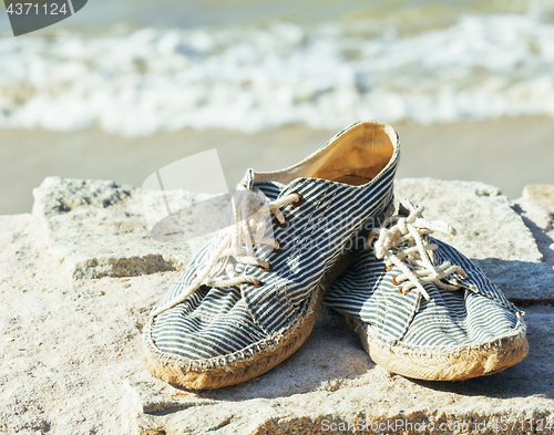 Image of picture of vintage old shabby sneakers at seacost, real forgotte