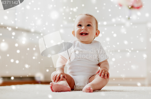 Image of happy baby boy or girl sitting on floor at home