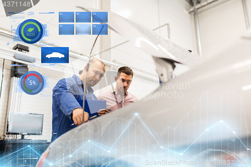 Image of auto mechanic with clipboard and man at car shop