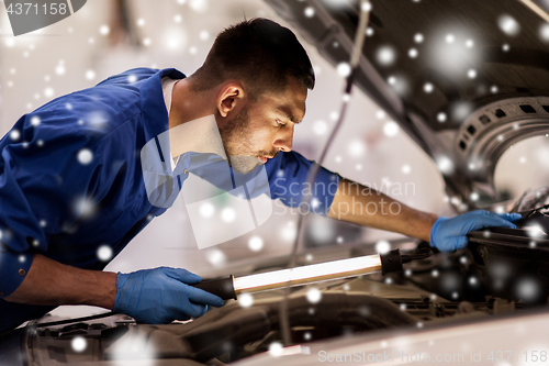 Image of mechanic man with lamp repairing car at workshop