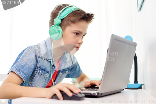 Image of boy in headphones playing video game on laptop