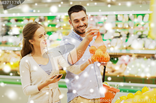 Image of happy couple buying oranges at grocery store