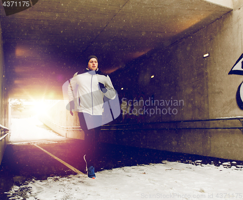 Image of man running along subway tunnel in winter