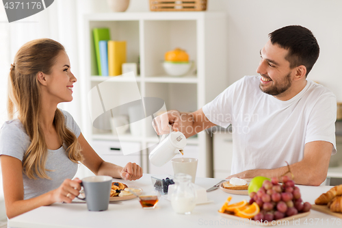 Image of happy couple having breakfast at home