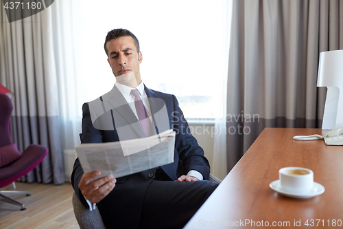 Image of businessman reading newspaper at hotel room