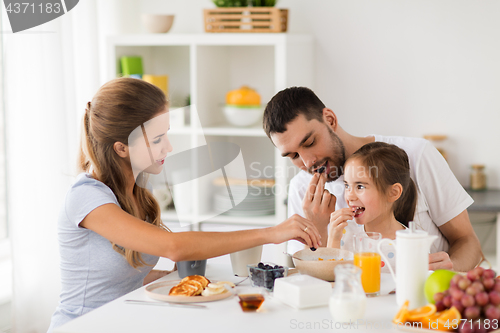 Image of happy family having breakfast at home