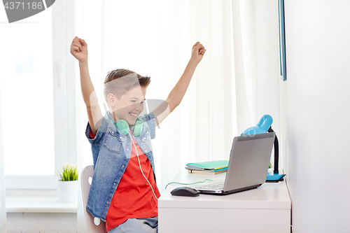 Image of boy with headphones playing video game on laptop