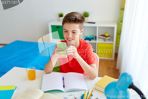 Image of student boy with smartphone distracting from study