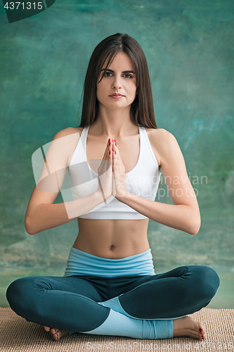 Image of Studio shot of a young woman doing yoga exercises on green background