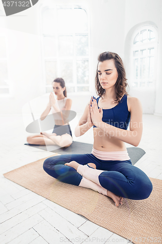 Image of Studio shot of a young women doing yoga exercises on white background