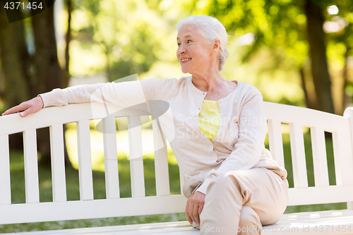 Image of happy senior woman sitting on bench at summer park