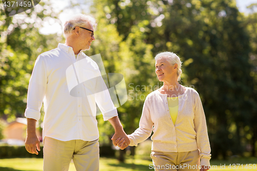 Image of happy senior couple walking at summer park